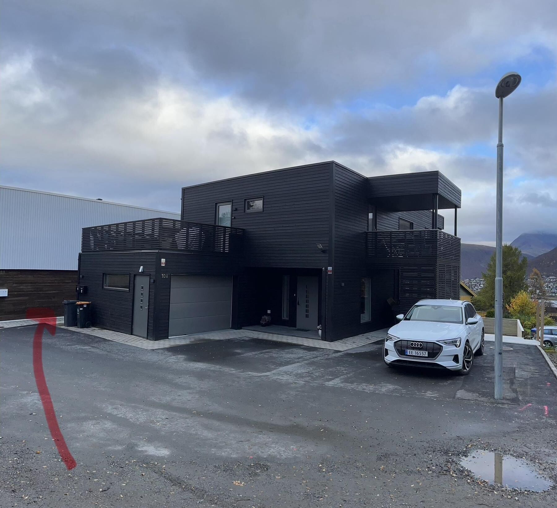 A modern building with a garage and a white car parked in front.