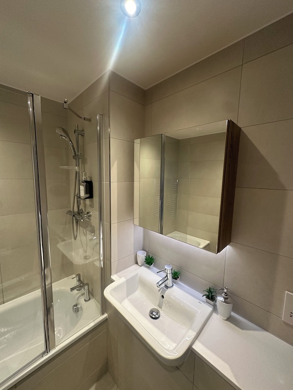 A modern bathroom with a glass-enclosed shower, a white sink, and a mirror above it.