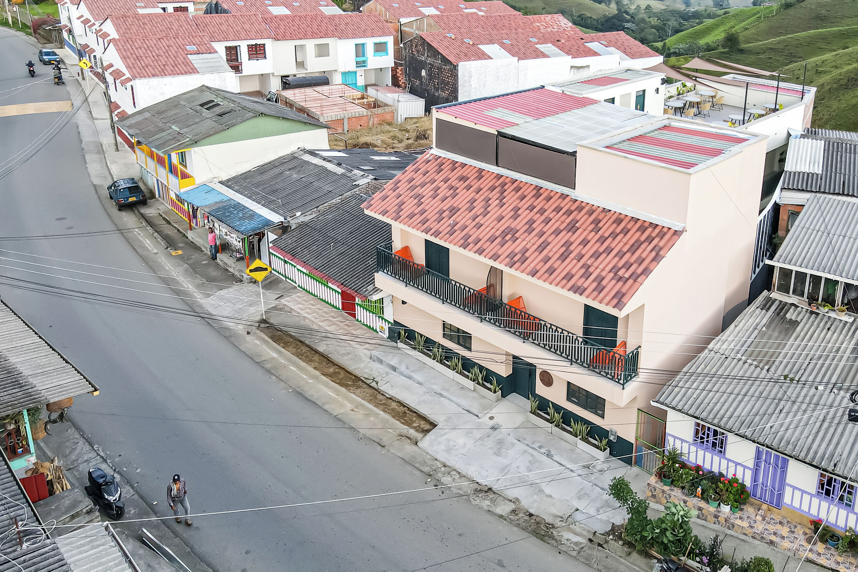 A multi-story building with a red-tiled roof, balconies, and a street in front.