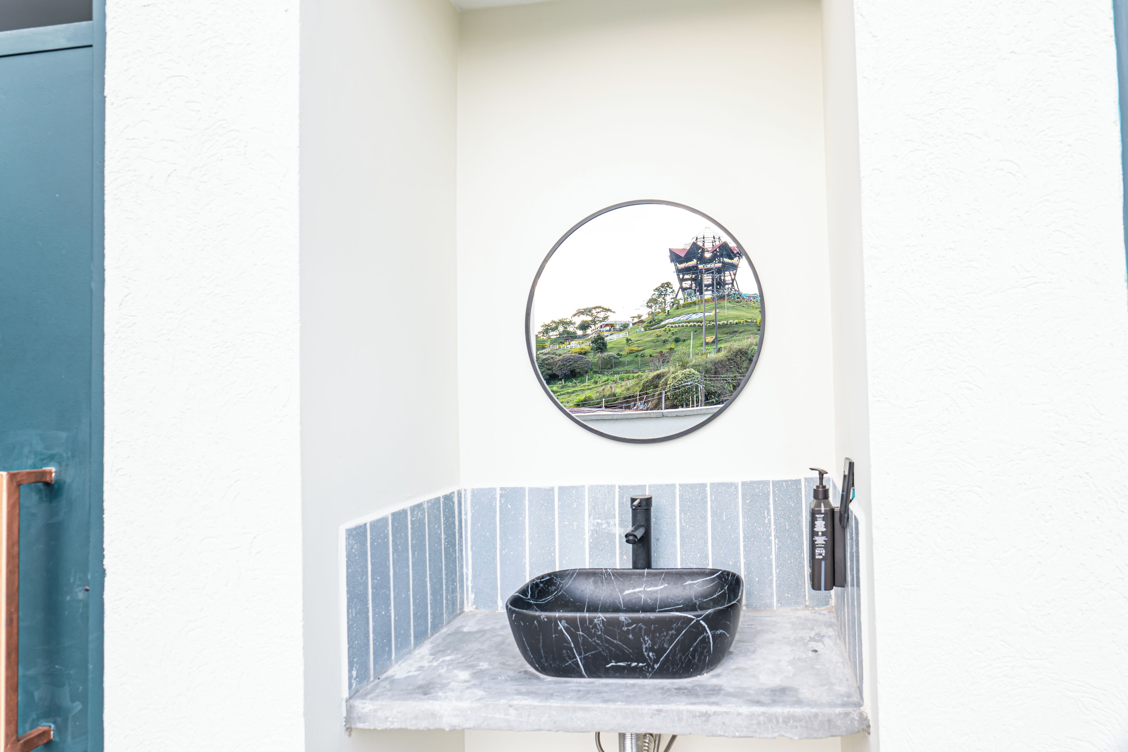 Un baño con lavamanos de mármol negro, un espejo redondo y una vista de un pagodas reflejada en el espejo.