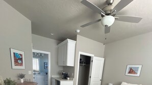 Una habitación pequeña con cama, escritorio y kitchenette.