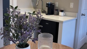 Una cocina con armarios blancos, una cafetera y una planta en maceta sobre la encimera.