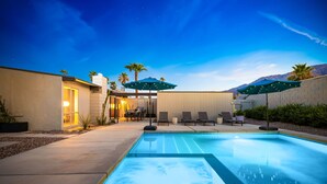 A swimming pool with lounge chairs and umbrellas, surrounded by a landscaped area with palm trees and a mountain backdrop. - 30+ Stay! Gorgeous Home W/Pool/Spa/Mtn Views (Palm Springs)
