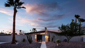 A modern house with a garage, a well-maintained garden with various plants, and a clear sky. - 30+ Stay! Gorgeous Home W/Pool/Spa/Mtn Views (Palm Springs)