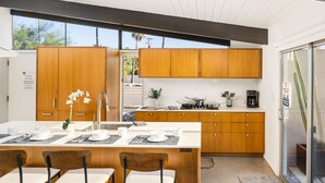 A modern kitchen with wooden cabinets, a central island with seating, and a large window providing natural light. - 30+ Stay! Gorgeous Home W/Pool/Spa/Mtn Views (Palm Springs)