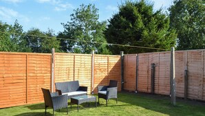 A fenced backyard with a patio area, outdoor furniture, and a wooden fence. - 2 bedroom accommodation in Firsby (Firsby)