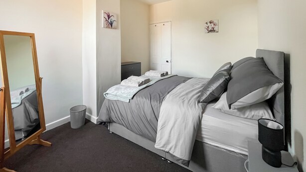 A bedroom with a bed, a bedside table, a mirror, a trash bin, and a wall-mounted coffee maker. - 2 bedroom accommodation in Firsby (Firsby)