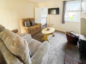 A living room with a sofa, a small table, a TV, and a window. - 2 bedroom accommodation in Firsby (Firsby)
