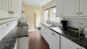 A kitchen with white cabinets, a black countertop, a coffee maker, and a window. - 2 bedroom accommodation in Firsby (Firsby)