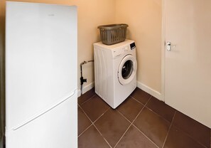 A laundry area with a washing machine, a basket on top, and a door.