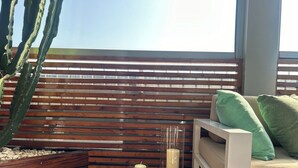 A wooden deck with a glass candle holder, a cactus, and a cushioned seating area with pillows. - Fiftyfive-one Zuretti (Milano)