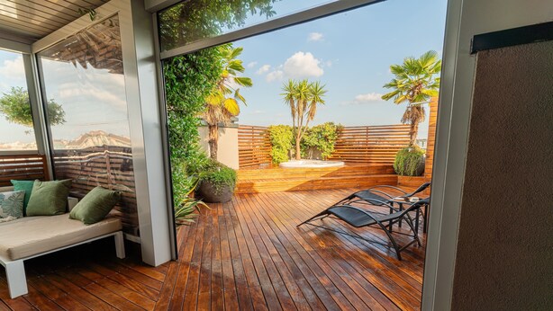 A wooden deck with a bench and lounge chairs, surrounded by plants and a wooden fence. - Fiftyfive-one Zuretti (Milano)
