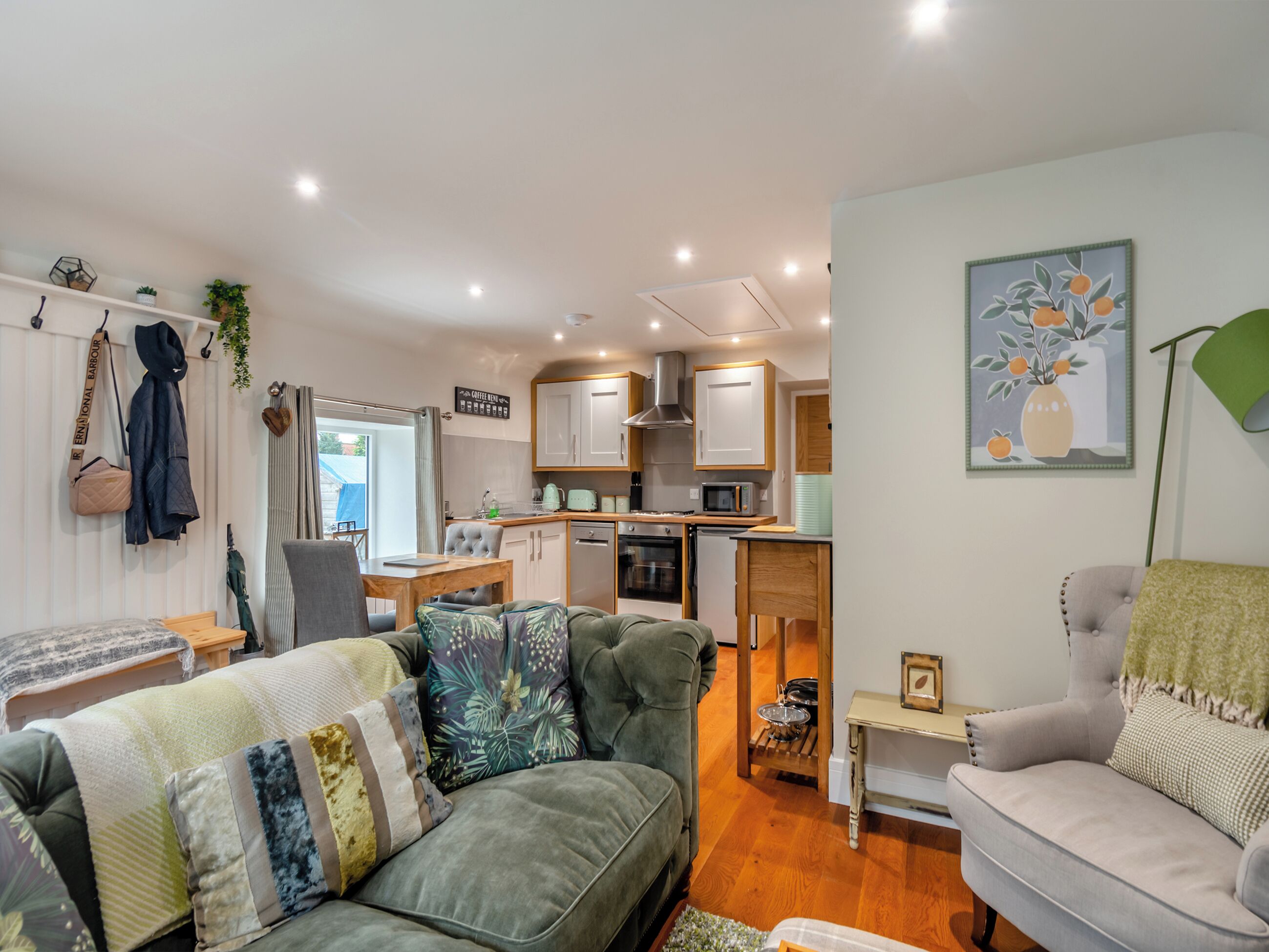 A compact living space with a kitchenette, a sofa, a dining table, and a chair.