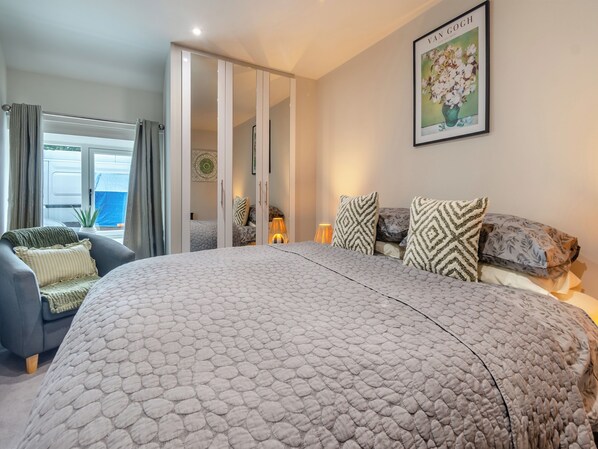 A bedroom with a large bed, a chair, a wardrobe, and a painting on the wall.