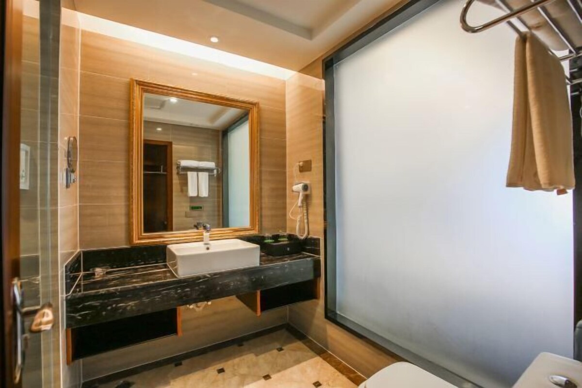 A modern bathroom with a large mirror, a sink, and a toilet.