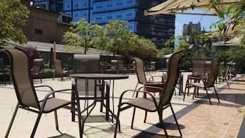 An outdoor seating area with tables and chairs, surrounded by buildings.