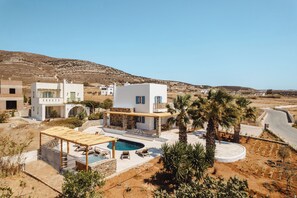 A modern villa with a pool, outdoor seating, and a view of the surrounding landscape.