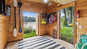 Una cabaña de madera con vista a un lago, un ventilador de techo y un extintor.