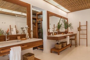 Une salle de bain moderne avec deux lavabos, de grands miroirs, des étagères en bois et un ventilateur de plafond.