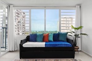 Relax in this stylish living room with a sofa, large windows, and a potted plant.