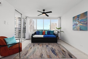 Relax in this stylish living room with a sofa, armchair, and patterned rug, offering a view of a high-rise building.