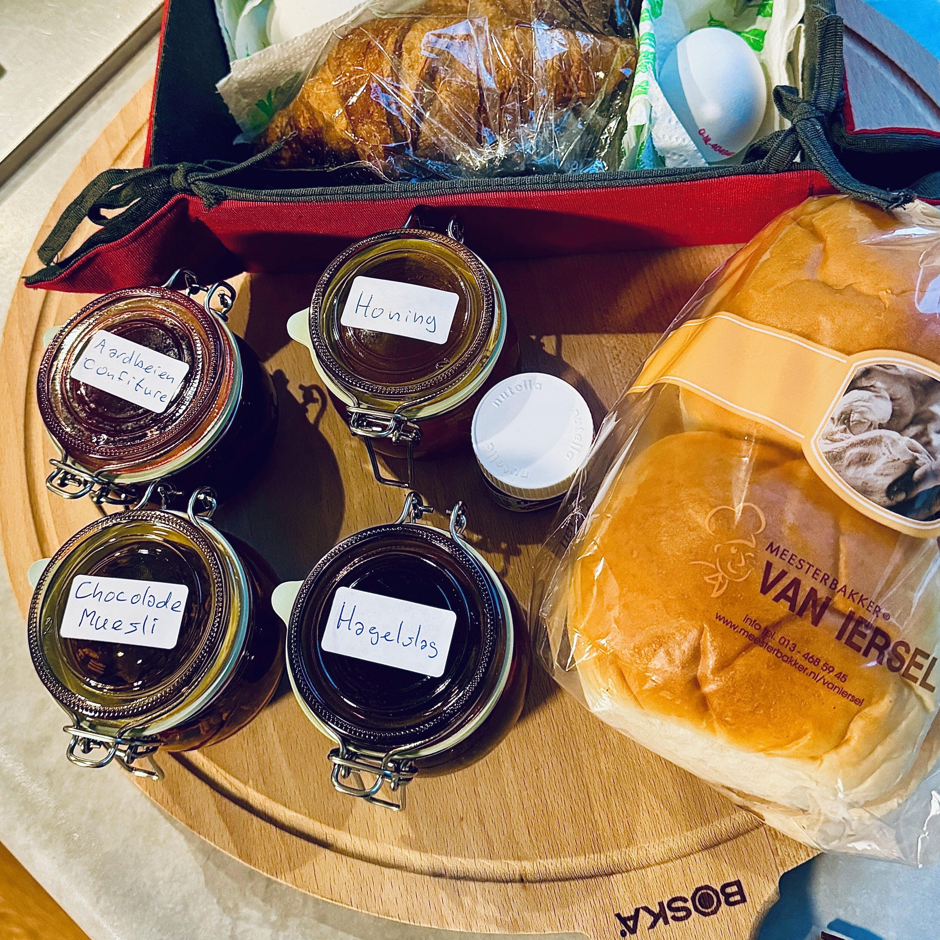 A tray with various food items including jars labeled with different types of honey, a loaf of bread, and a package of cookies.