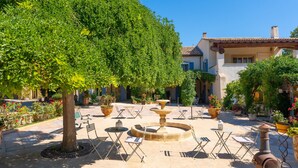 A courtyard with a fountain, outdoor seating, and potted plants.