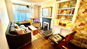 A living room with a sofa, a television, a fireplace, and a bookshelf. - Shepherds Bush W12 Magical Townhouse nr Westfield (London)