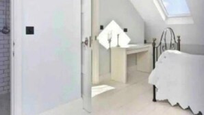 A bedroom with a skylight, a bed, and a bathroom with a sink and mirror. - Shepherds Bush W12 Magical Townhouse nr Westfield (London)