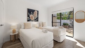 A bedroom with two beds, a large window, and a view of the outdoors.
