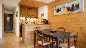 A modern kitchen with wooden cabinetry, a checkered backsplash, and a dining area with a table and chairs.