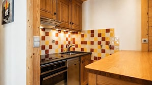 A kitchen with wooden cabinets, a tiled backsplash, a stainless steel sink, and a wooden countertop.