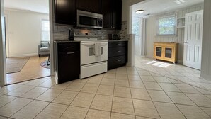 A modern kitchen with dark cabinetry, a built-in microwave, a double oven, and a small wooden cabinet. - House at Guilford Hills (Greensboro)