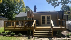 A house with a wooden deck, a stone pathway, and a covered patio area. - House at Guilford Hills (Greensboro)