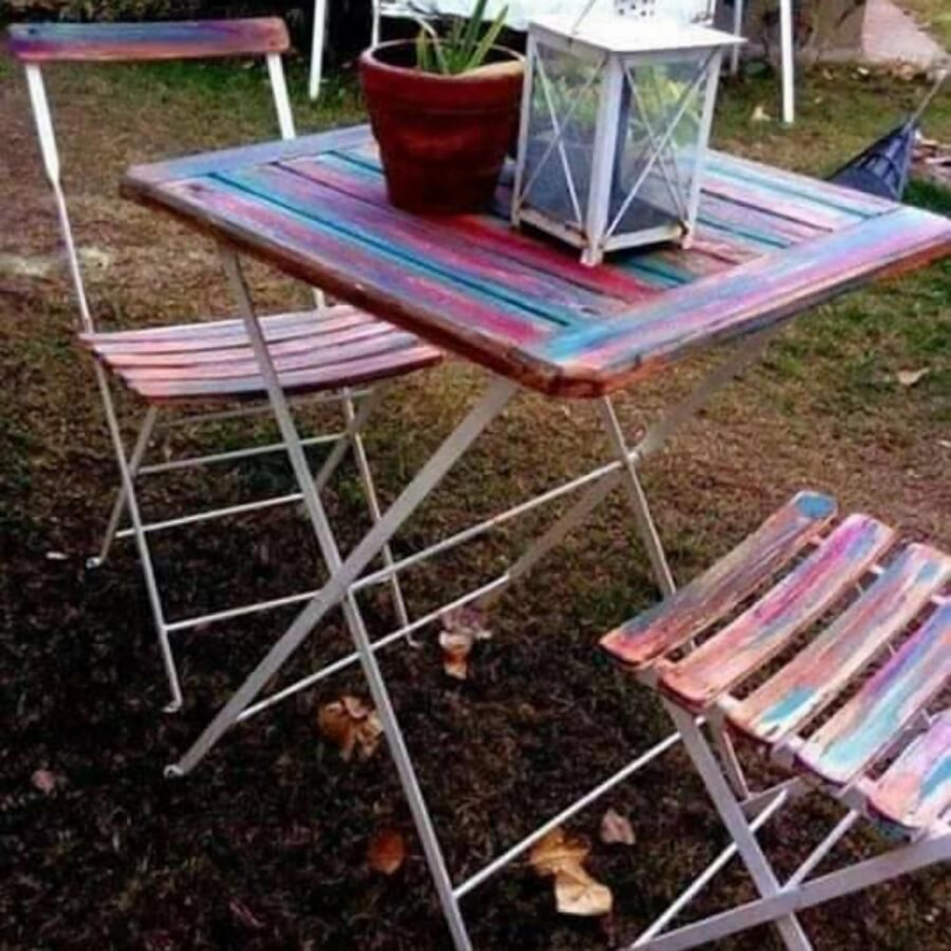 Een kleurrijke buitentafel met metalen frame, een potplant en een lantaarn.