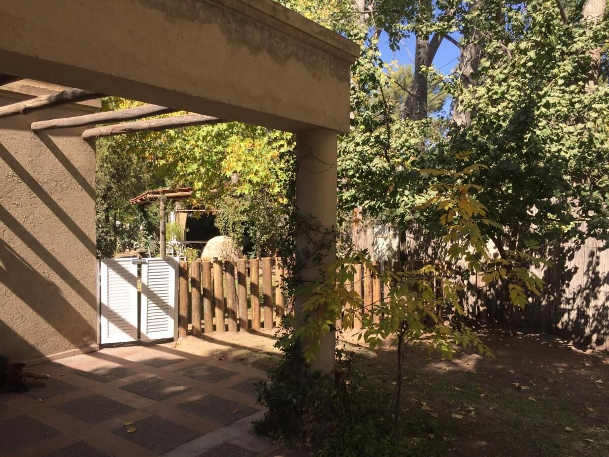 A covered outdoor area with a wooden fence, a small tree, and a concrete structure.
