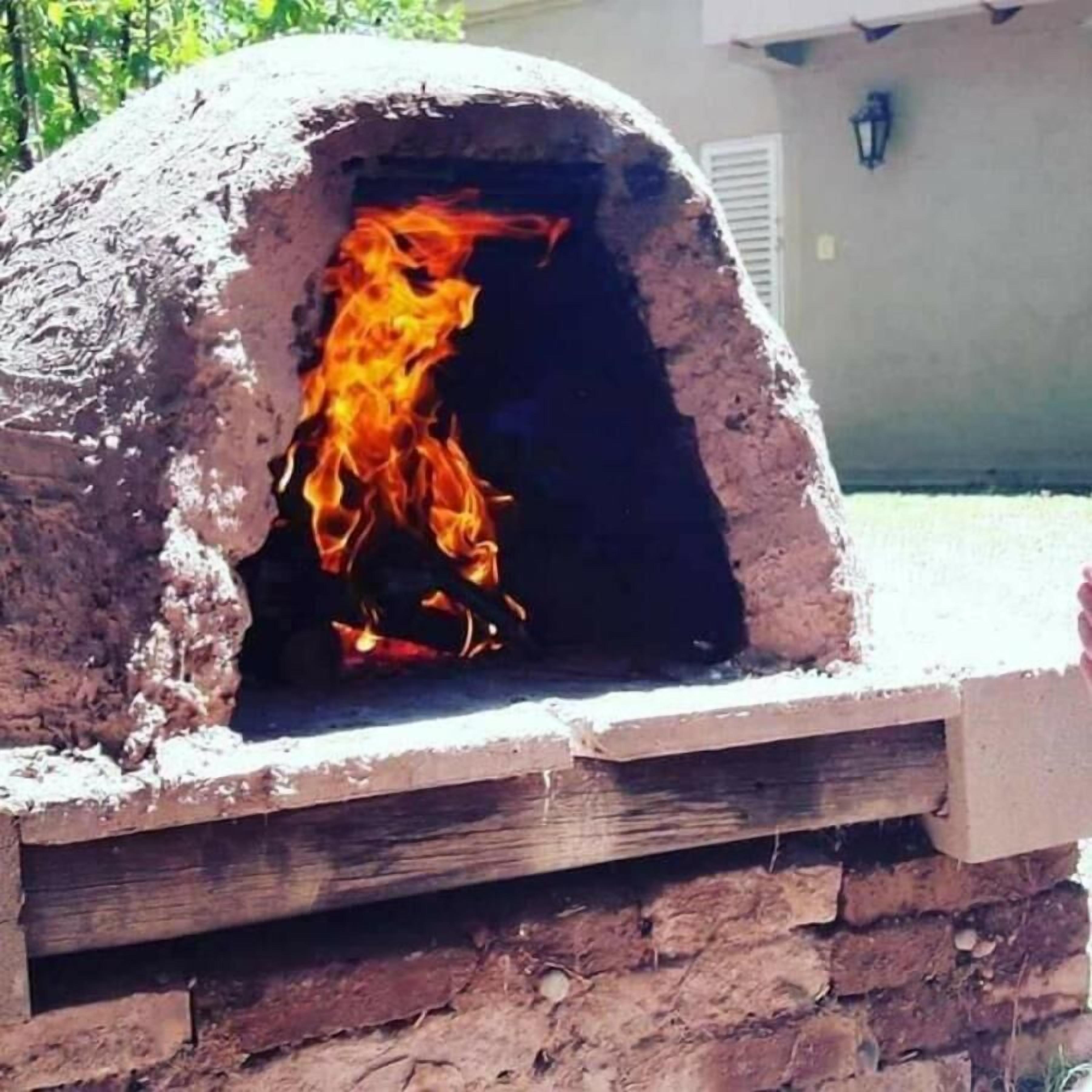 A traditional brick oven with a fire inside, likely used for cooking or baking.