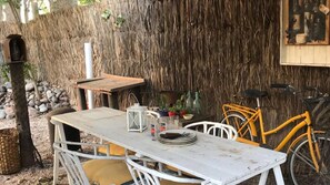Relax in a serene outdoor space with a patio table, pitcher, and plants, surrounded by a wooden fence and a charming wooden structure.