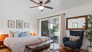 Une chambre à coucher avec un lit, un ventilateur de plafond, un grand miroir, une chaise et un tapis en peau de vache.