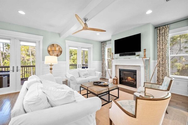 A living room with a fireplace, white sofas, a coffee table, and a TV.