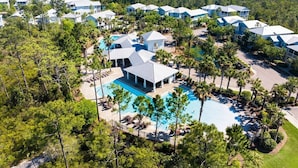 A resort with multiple buildings, a central pool, and surrounding palm trees.