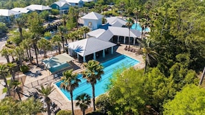 A resort with multiple buildings, a central swimming pool, and surrounding palm trees.