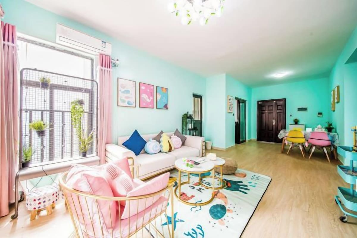 A room with a sofa, a small round table, a window with curtains, and a door.
