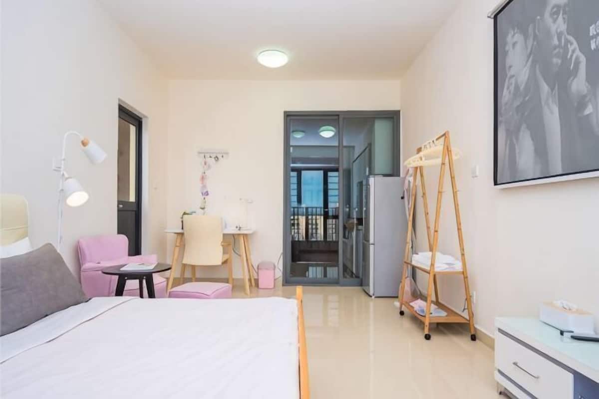 Een hotelkamer met een bed, bureau, stoel, lamp, kledingkast en een balkon met een balustrade.