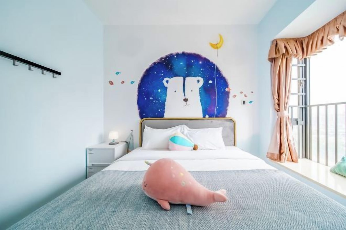 A bedroom with a bed, a nightstand, a plush toy, and a wall mural.
