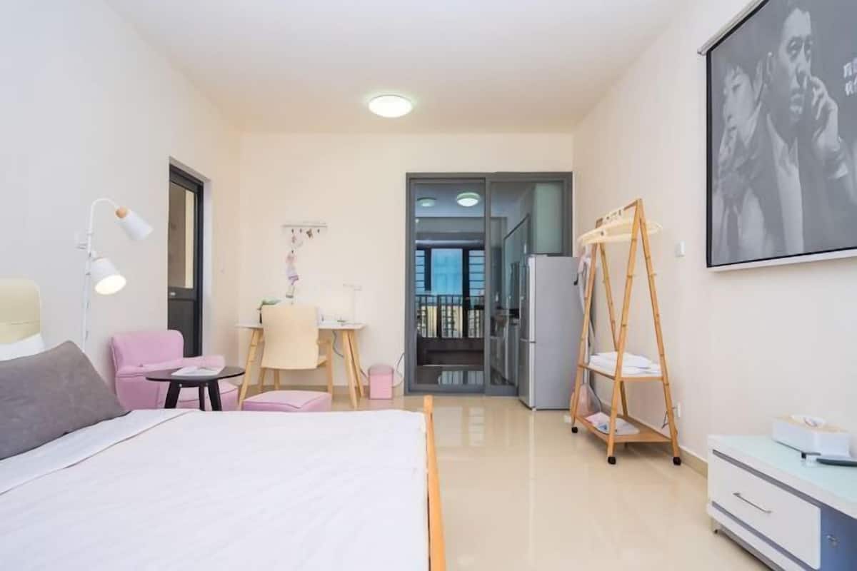 Een slaapkamer met een bed, een bureau, een stoel, een kledingkast, een spiegel en een deur naar een balkon.