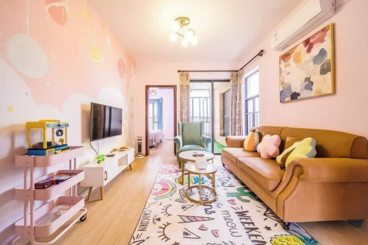 Een gezellige woonkamer met een bank, televisie en een kleurrijk tapijt.