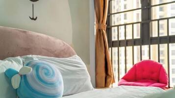 Een bed met een roze hoofdbord, een kussen met een blauw-witte spiraal en een rode stoel.
