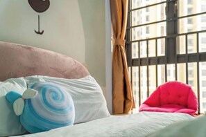 A bed with a pink headboard, a blue and white swirl pillow, and a red chair. - Dream House (Zhuhai)
