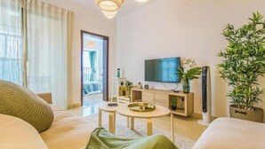 Un salon moderne avec un canapé, une table basse, un téléviseur et une plante en pot.